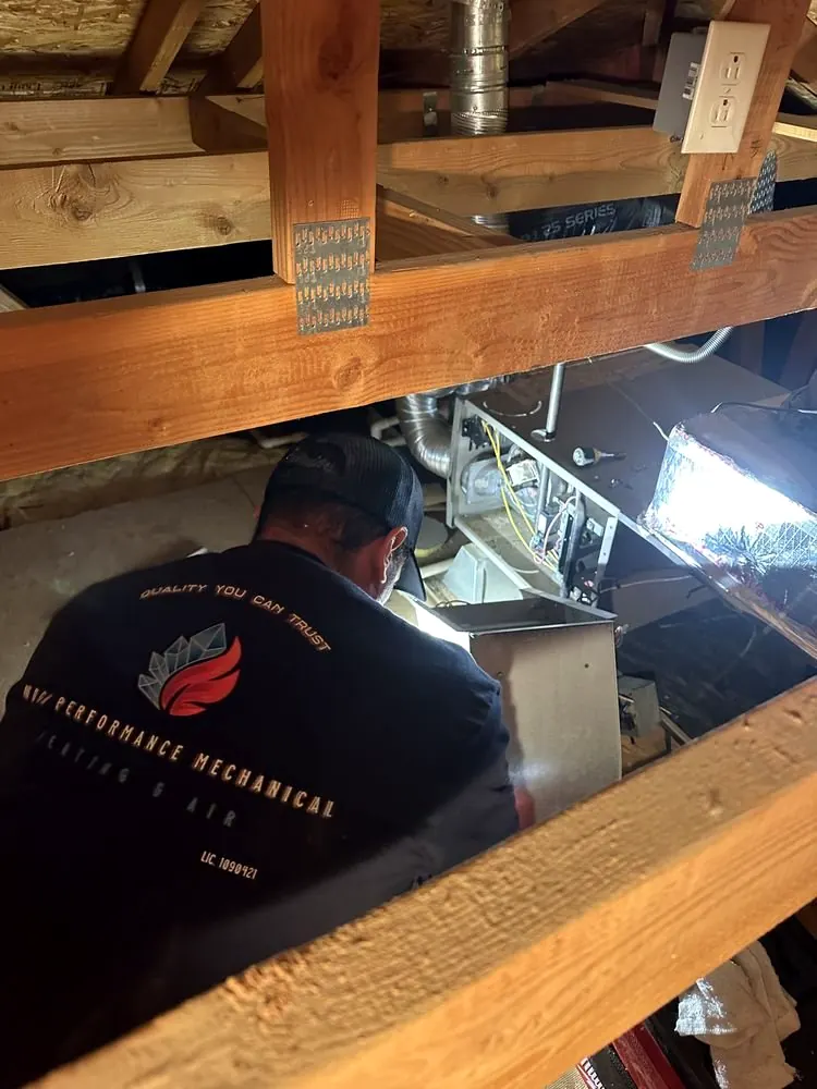 High Performance Mechanical technician working on heating equipment in an attic